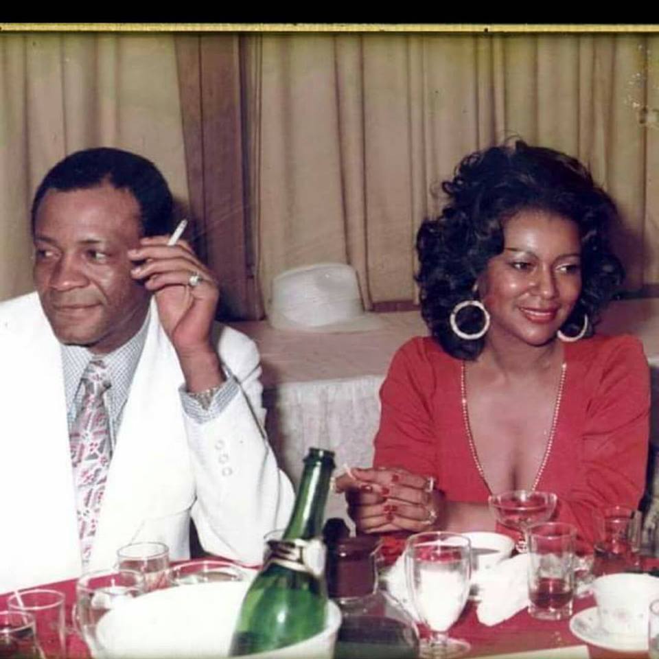 Joe et Sylvia Robinson souriants assis à une table de restaurant en train de fumer.